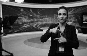 Intérprete de LIBRAS realizando tradução simultânea em convenção corporativa para público surdo.